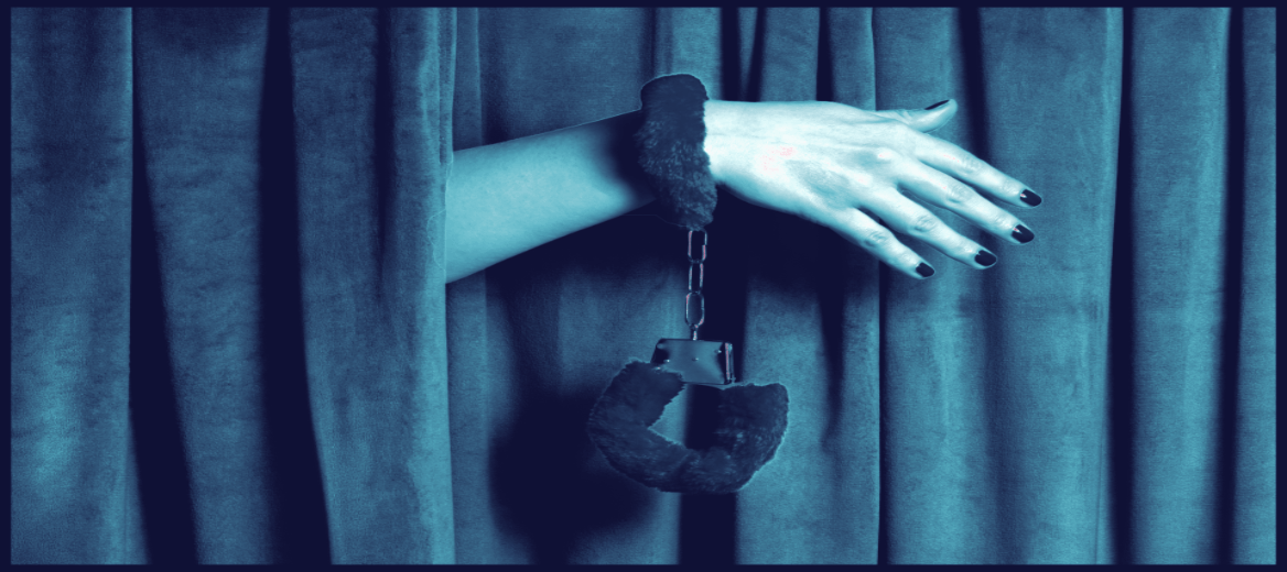 A woman’s hand reaches out from a curtain, wearing soft, furry handcuffs.